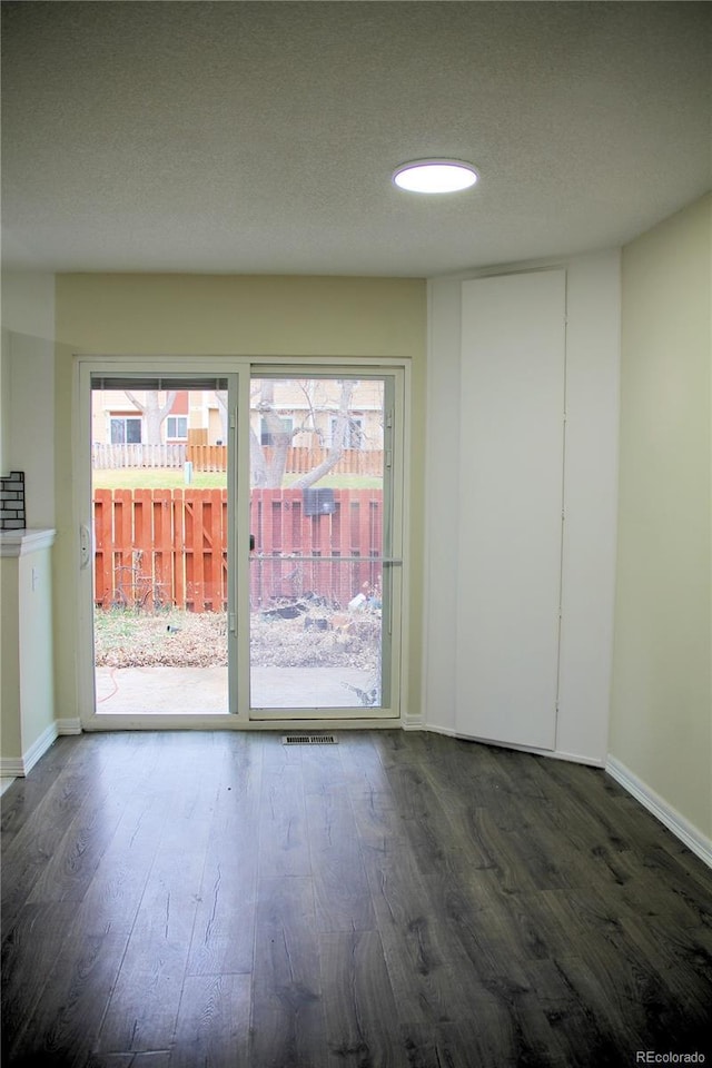 spare room featuring a textured ceiling and dark hardwood / wood-style floors