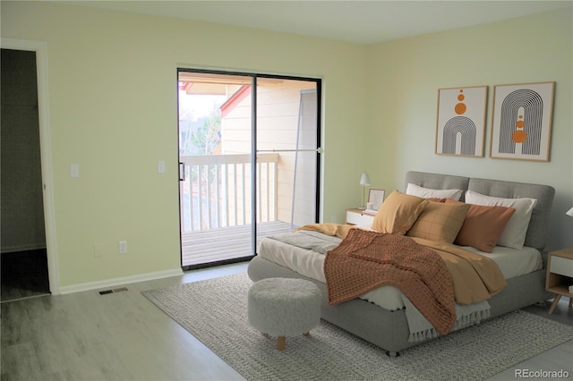 bedroom with access to exterior, a walk in closet, and hardwood / wood-style flooring