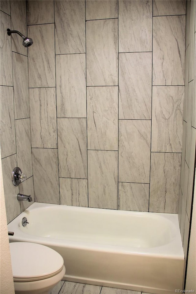 bathroom with toilet and tiled shower / bath