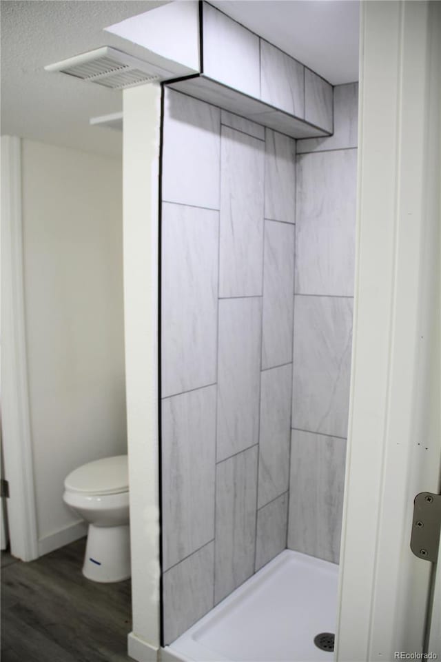 bathroom with a shower, hardwood / wood-style floors, a textured ceiling, and toilet