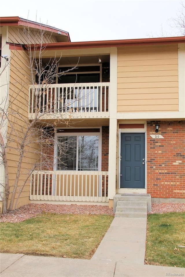 view of front of house with a balcony and brick siding