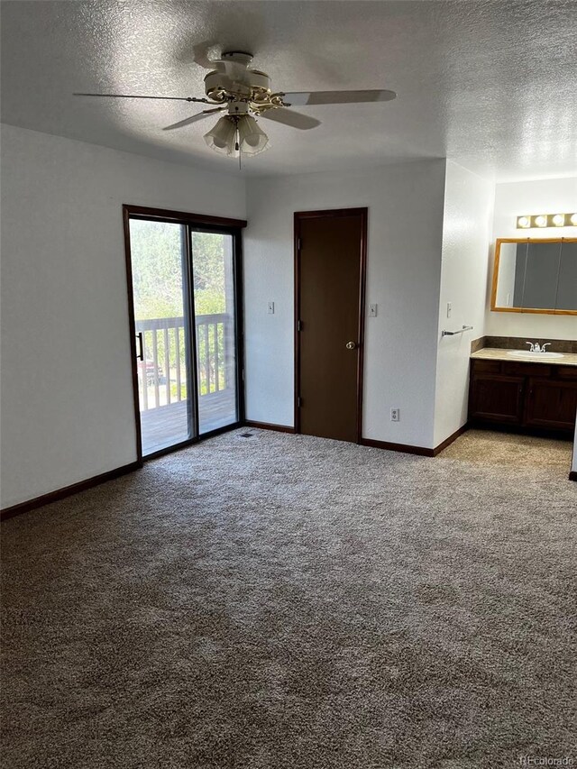 interior space featuring ensuite bathroom, sink, a textured ceiling, light carpet, and ceiling fan