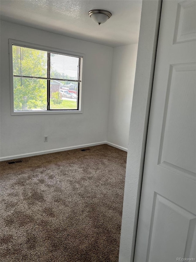 spare room with a textured ceiling and carpet