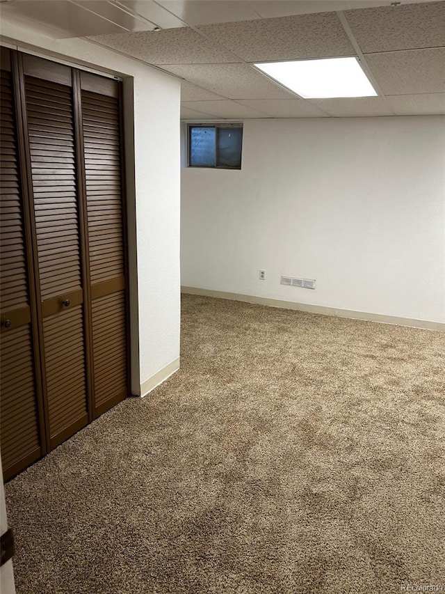 basement featuring a paneled ceiling and carpet floors