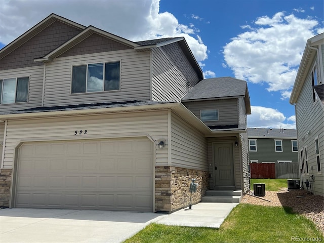 522 Foxtail Pl, Wiggins, CO 80654 - view of front of house with stone siding, central air condition unit, an attached garage, and concrete driveway
