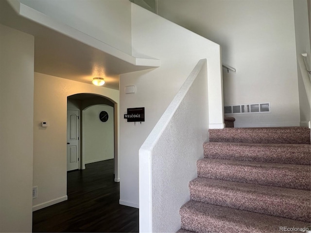 522 Foxtail Pl, Wiggins, CO 80654 - staircase with wood finished floors, arched walkways, and baseboards