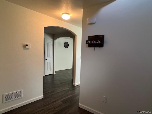 522 Foxtail Pl, Wiggins, CO 80654 - hallway with arched walkways, baseboards, and dark wood finished floors