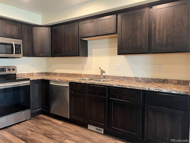522 Foxtail Pl, Wiggins, CO 80654 - kitchen with stainless steel appliances, a sink, wood finished floors, and dark brown cabinets