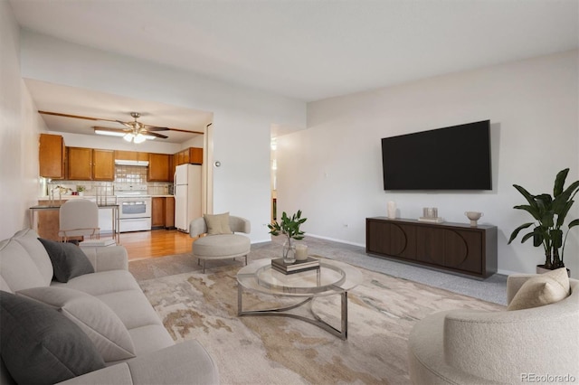 living room with baseboards, a ceiling fan, and light colored carpet