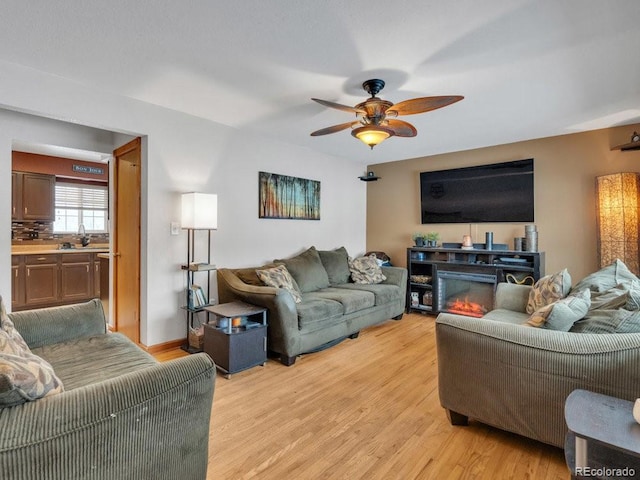 living room with ceiling fan, sink, and light hardwood / wood-style floors