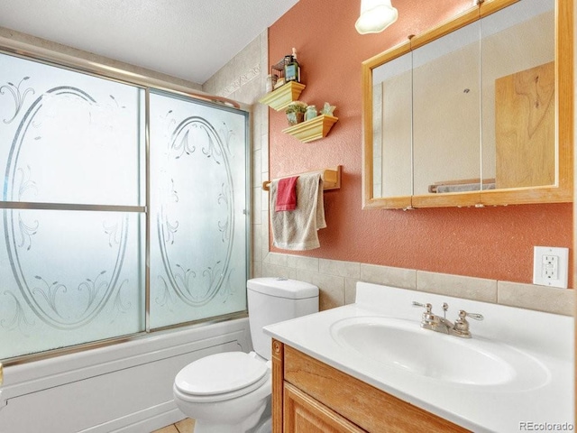 full bathroom with combined bath / shower with glass door, tile walls, vanity, toilet, and a textured ceiling