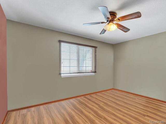 empty room with a textured ceiling, ceiling fan, and light wood-type flooring