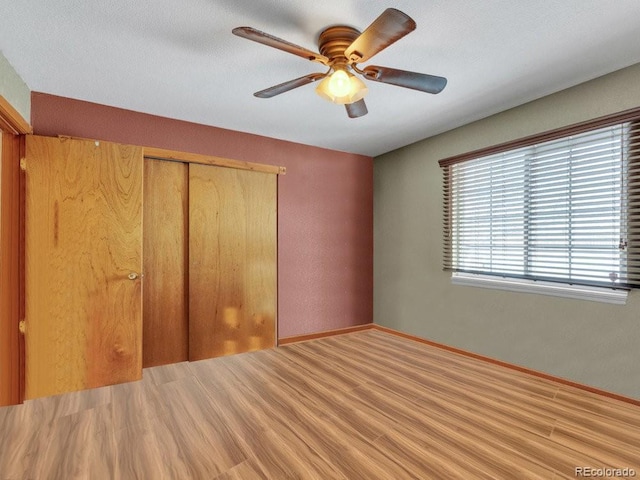 unfurnished bedroom featuring a closet, ceiling fan, and light wood-type flooring