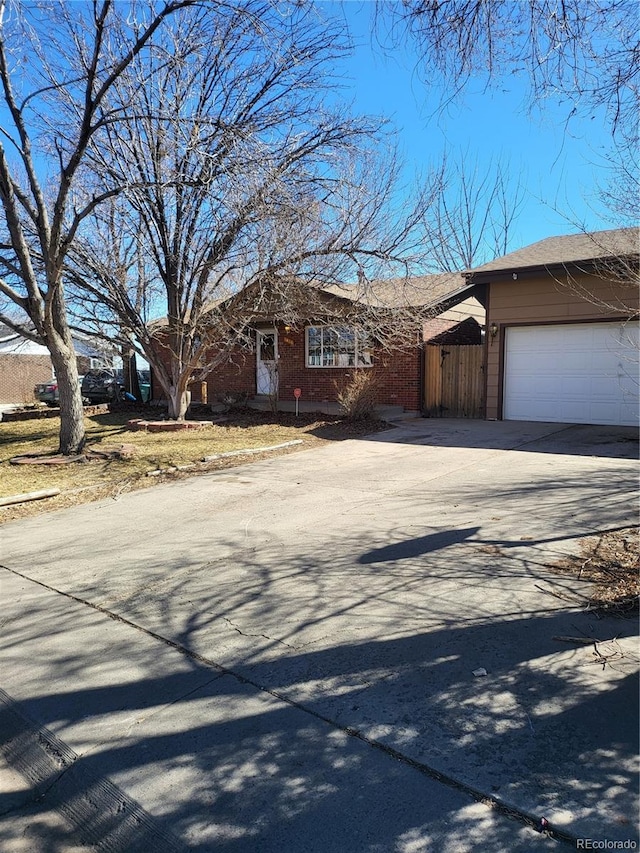 view of front of property with an attached garage, fence, brick siding, and driveway