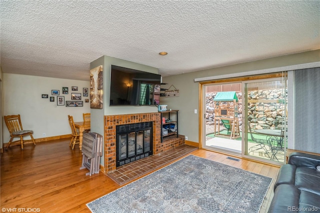 155 Xenon St Unit 33, Lakewood, CO 80228 - living room featuring wood finished floors, a brick fireplace, a textured ceiling, and baseboards