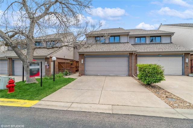 155 Xenon St Unit 33, Lakewood, CO 80228 - view of front of house featuring brick siding, driveway, roof with shingles, and a garage