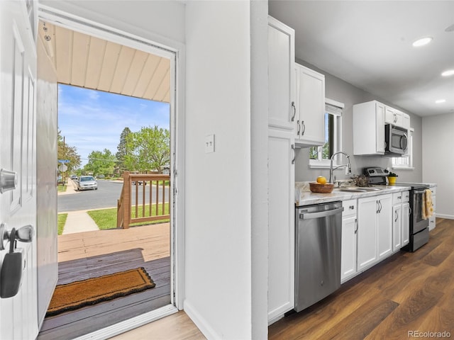 kitchen featuring stainless steel appliances, a sink, dark wood-style flooring, white cabinets, and recessed lighting
