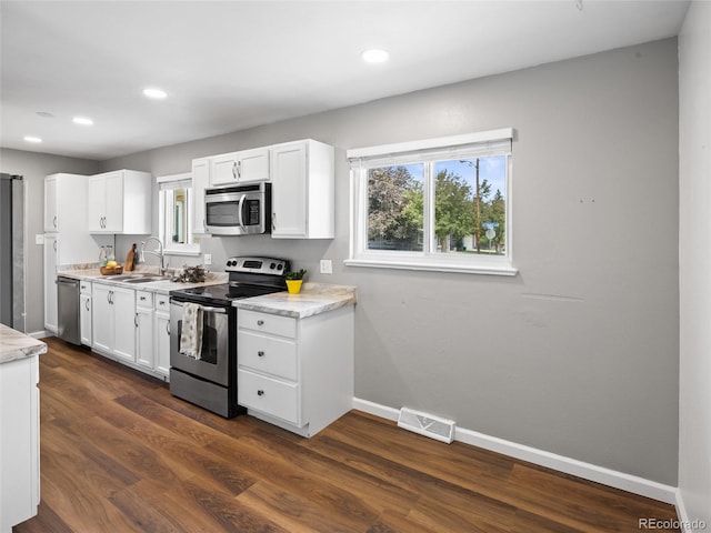 kitchen featuring stainless steel appliances, a sink, baseboards, white cabinets, and light countertops