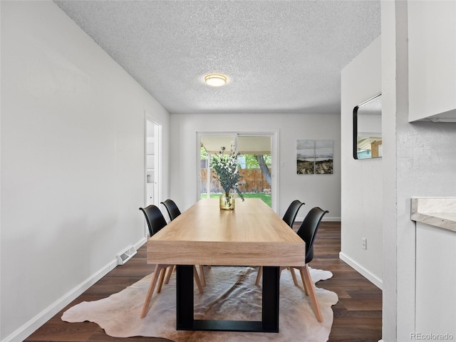 dining room with a textured ceiling, dark wood finished floors, and baseboards