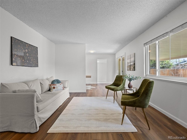 living room with a textured ceiling, wood finished floors, and baseboards
