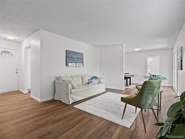 living room with a textured ceiling, wood finished floors, and baseboards
