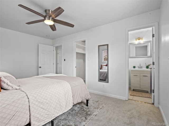 carpeted bedroom with ensuite bathroom, baseboards, a sink, and a ceiling fan
