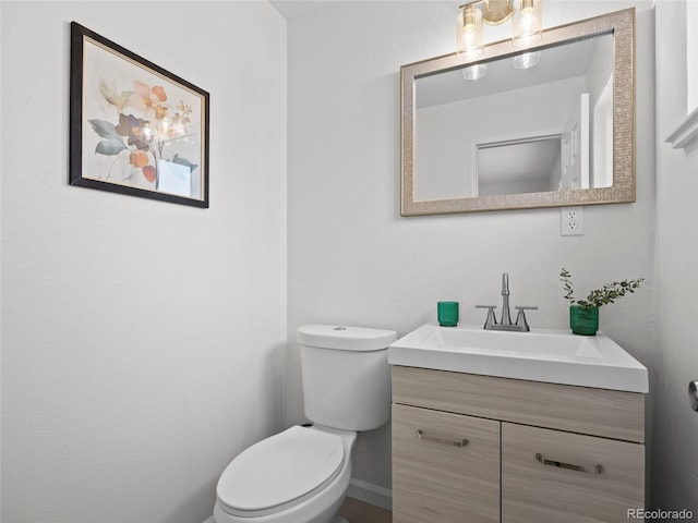 bathroom featuring toilet, vanity, and baseboards