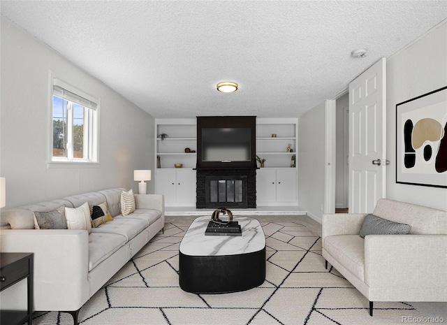 living room featuring built in shelves, a textured ceiling, and a brick fireplace