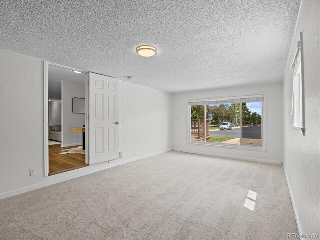 unfurnished bedroom with a textured ceiling, carpet flooring, and baseboards