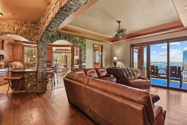 living room featuring a tray ceiling, hardwood / wood-style flooring, sink, and ornamental molding