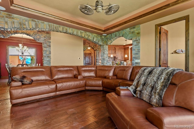 living room featuring wood-type flooring, a chandelier, a tray ceiling, and ornamental molding