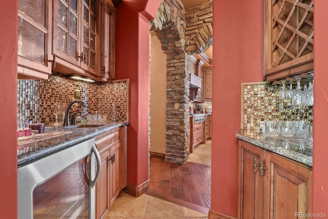 kitchen featuring dark stone counters, beverage cooler, tasteful backsplash, sink, and light tile floors