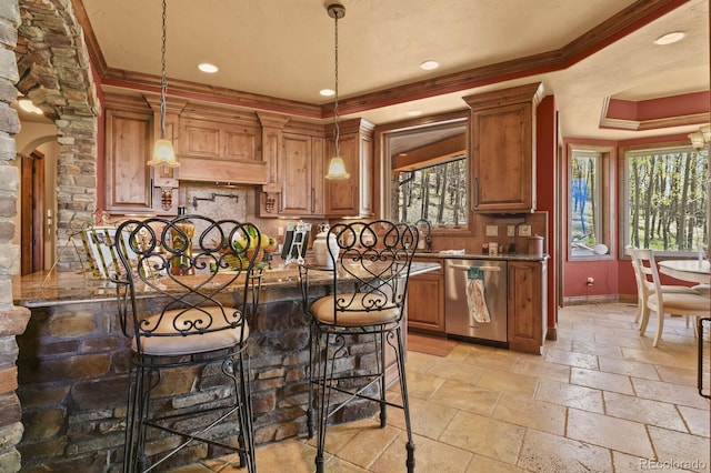 kitchen with ornamental molding, decorative light fixtures, dishwasher, light tile floors, and a raised ceiling