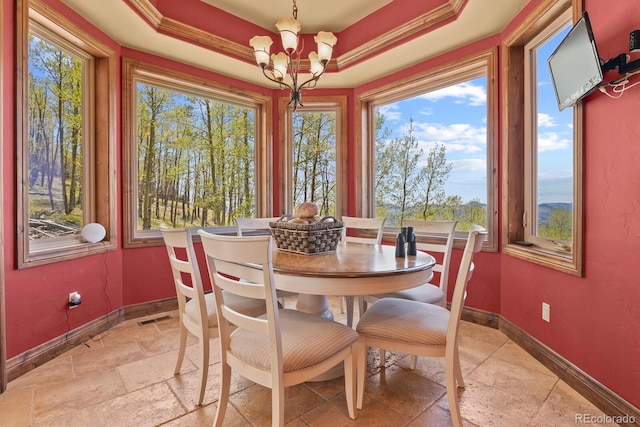 tiled dining space with a notable chandelier, a raised ceiling, and ornamental molding