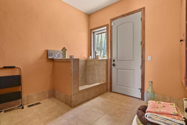 bathroom with tile flooring and a bath