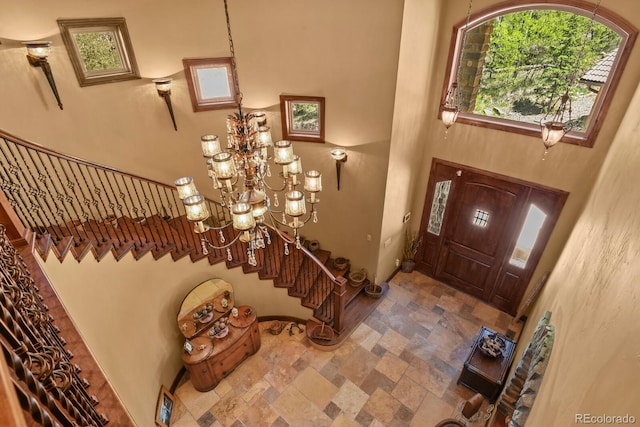 tiled entryway featuring a notable chandelier and a towering ceiling