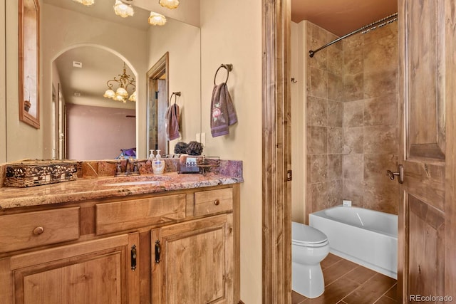 full bathroom featuring tile walls, a notable chandelier, toilet, tiled shower / bath combo, and vanity