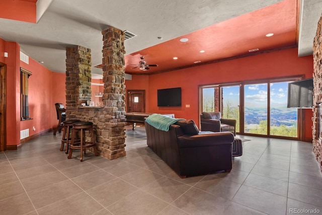 living room with ornate columns, ceiling fan, and tile floors