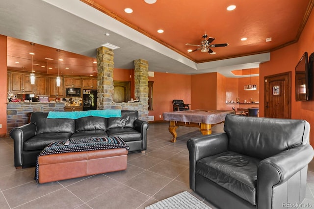 living room featuring ceiling fan, a tray ceiling, decorative columns, tile floors, and pool table