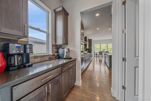 9433 Torrey Way, Arvada, CO 80007 - kitchen with dark brown cabinets, wood finished floors, backsplash, recessed lighting, and oven