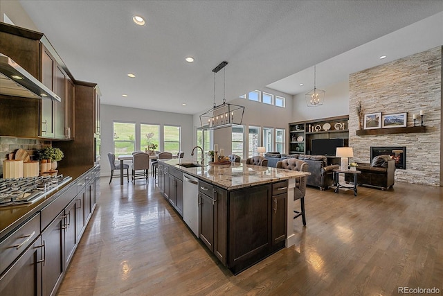 9433 Torrey Way, Arvada, CO 80007 - kitchen with stainless steel appliances, dark brown cabinetry, a sink, a chandelier, and a center island with sink