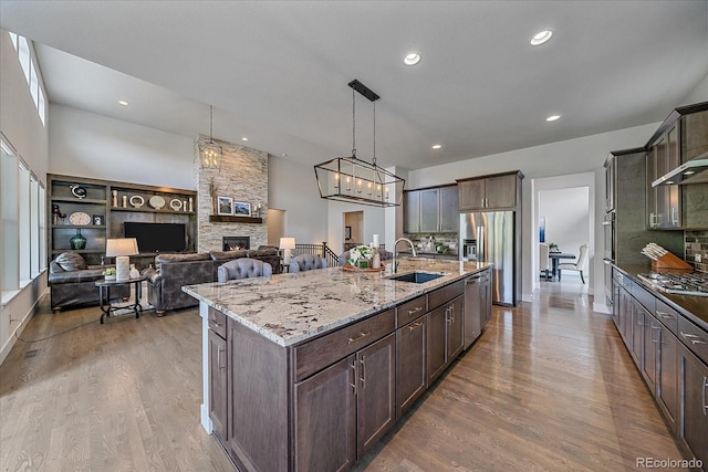 9433 Torrey Way, Arvada, CO 80007 - kitchen with a sink, wood finished floors, stainless steel appliances, a fireplace, and light stone counters