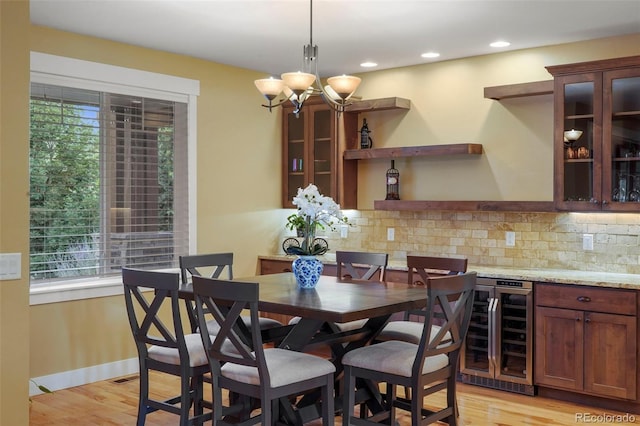 dining area featuring an inviting chandelier, light hardwood / wood-style floors, and beverage cooler