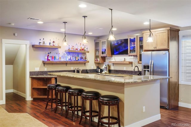 bar with dark hardwood / wood-style flooring, stainless steel fridge with ice dispenser, decorative light fixtures, and light stone countertops