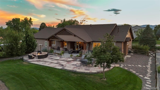 back house at dusk featuring a yard, a patio area, and outdoor lounge area