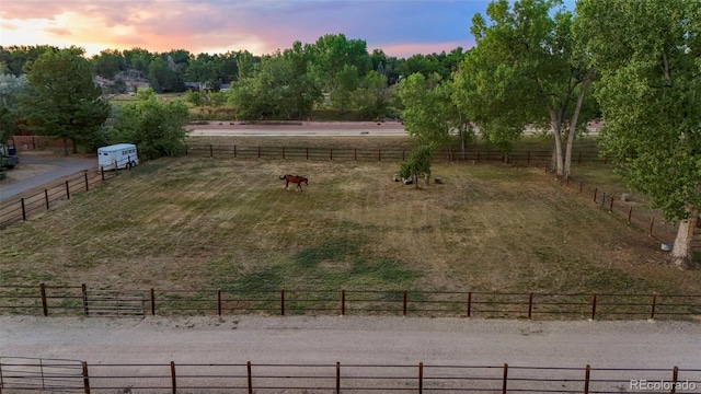 yard at dusk featuring a rural view