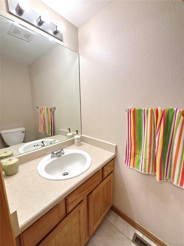 2835 S Tower Way, Aurora, CO 80013 - half bathroom featuring vanity, tile patterned floors, toilet, and a textured wall