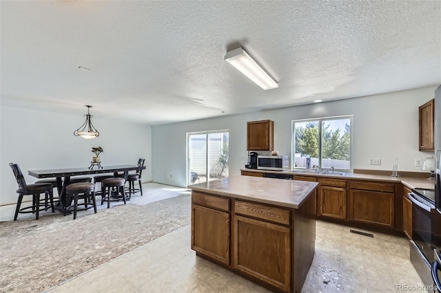 20530 Randolph Pl, Denver, CO 80249 - kitchen featuring appliances with stainless steel finishes, a center island, a textured ceiling, hanging light fixtures, and light flooring