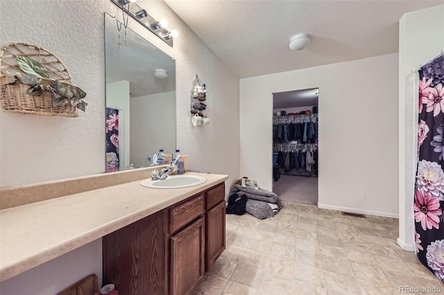 20530 Randolph Pl, Denver, CO 80249 - full bathroom featuring vanity, a textured wall, a spacious closet, and a textured ceiling