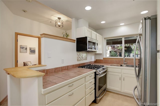 1460 Quince Ave Unit 102, Boulder, CO 80304 - kitchen featuring stainless steel appliances, white cabinets, tile countertops, recessed lighting, and a peninsula